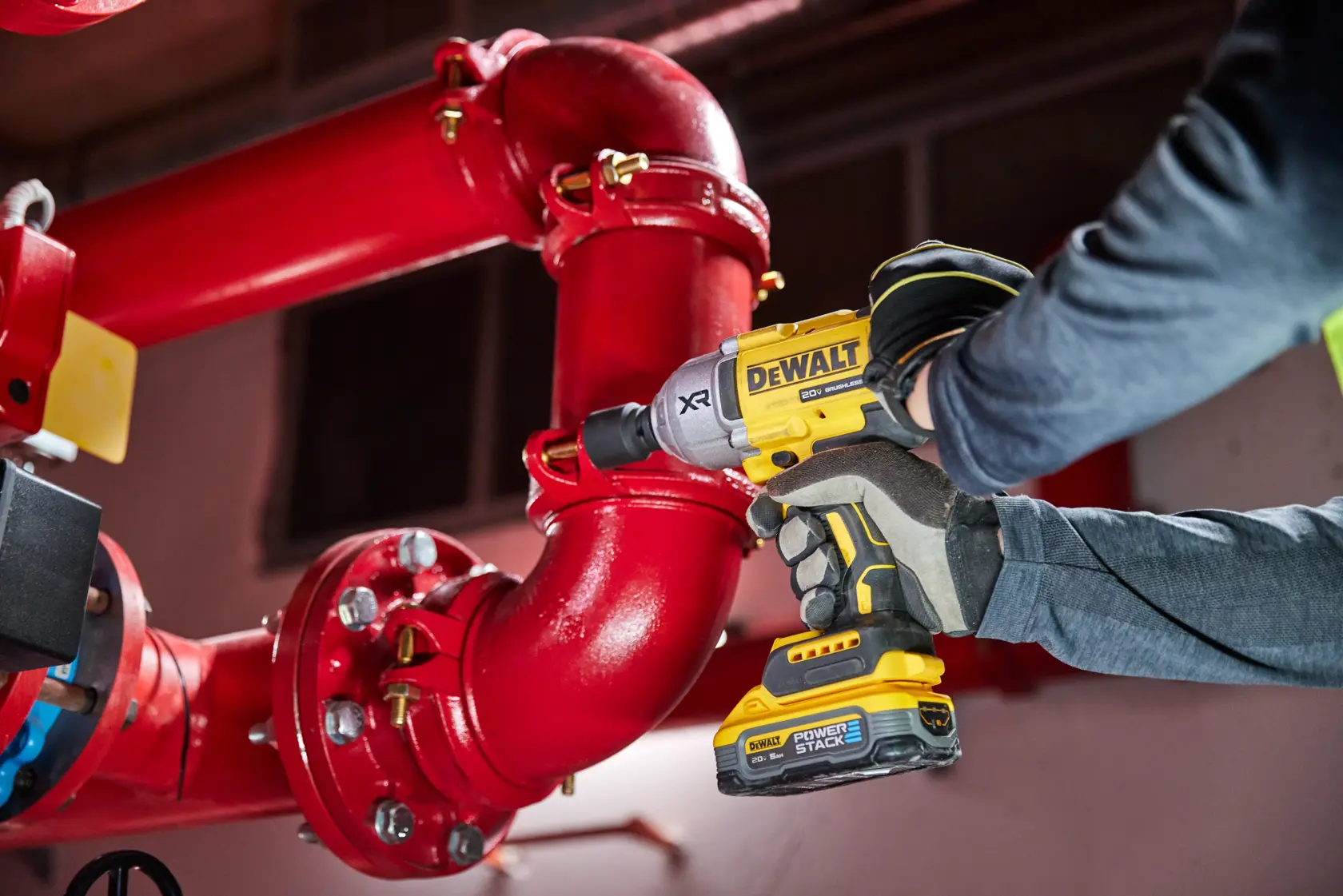 Impact wrench being used on large pipe with DEWALT POWERSTACK five amp hour battery