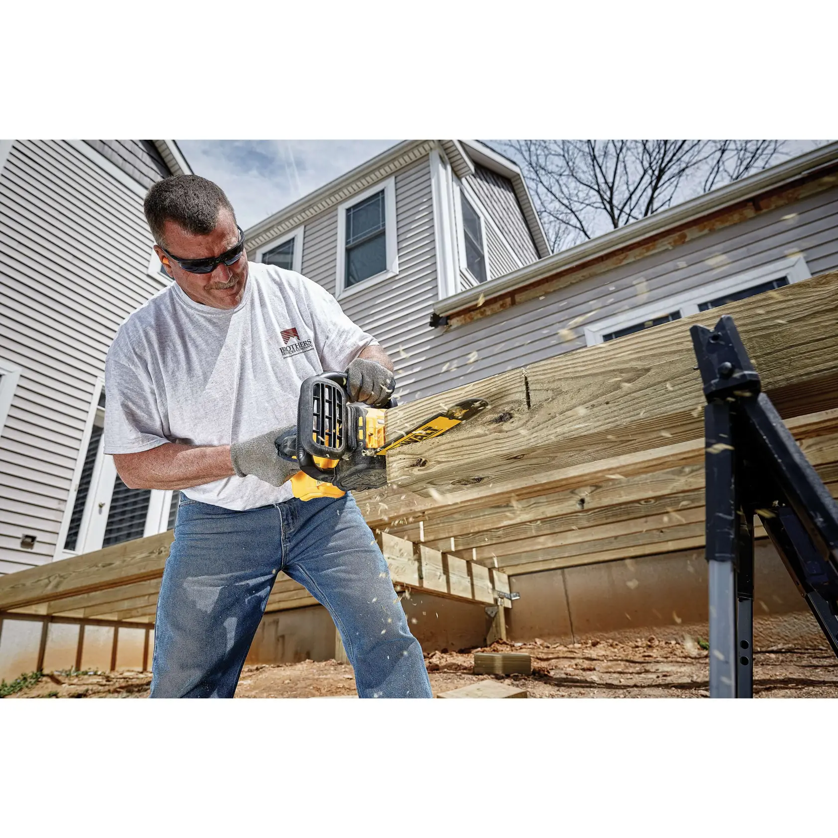 XR® Compact 12 inch Cordless Chainsaw being used by a worker to cut through a square log of wood at a worksite