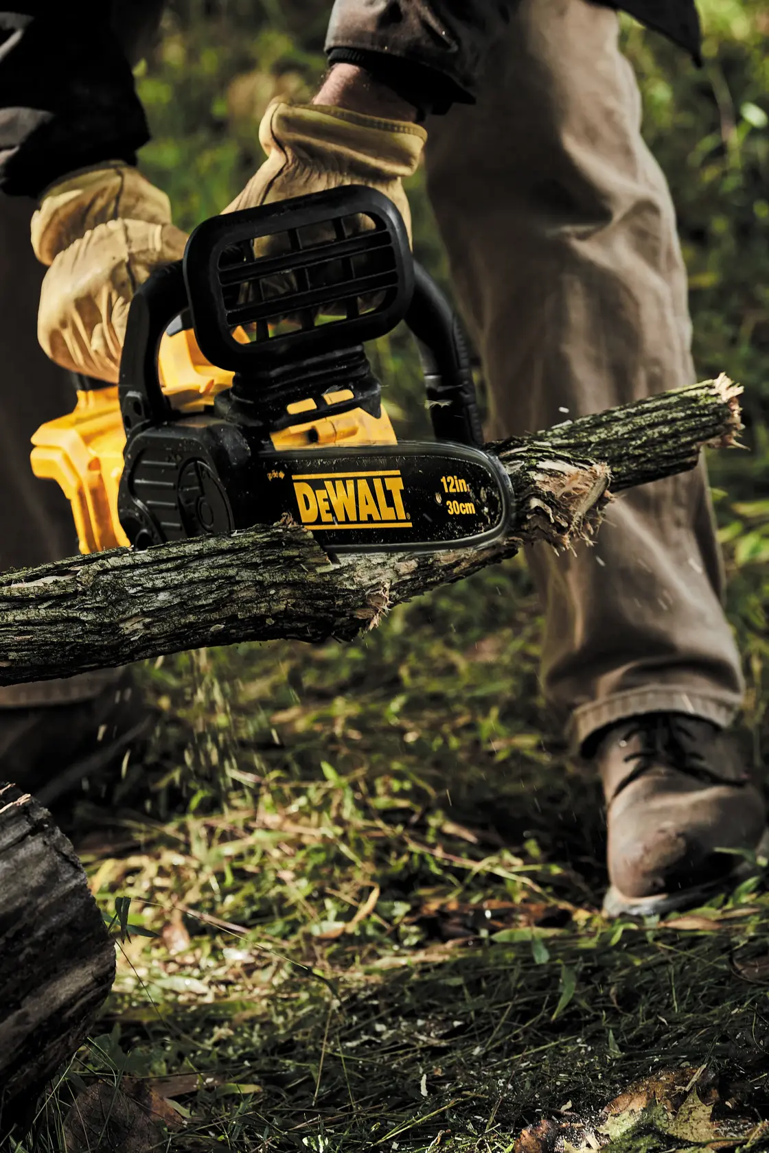 20 volt max x r compact 12 inch cordless chainsaw being used to saw a branch.