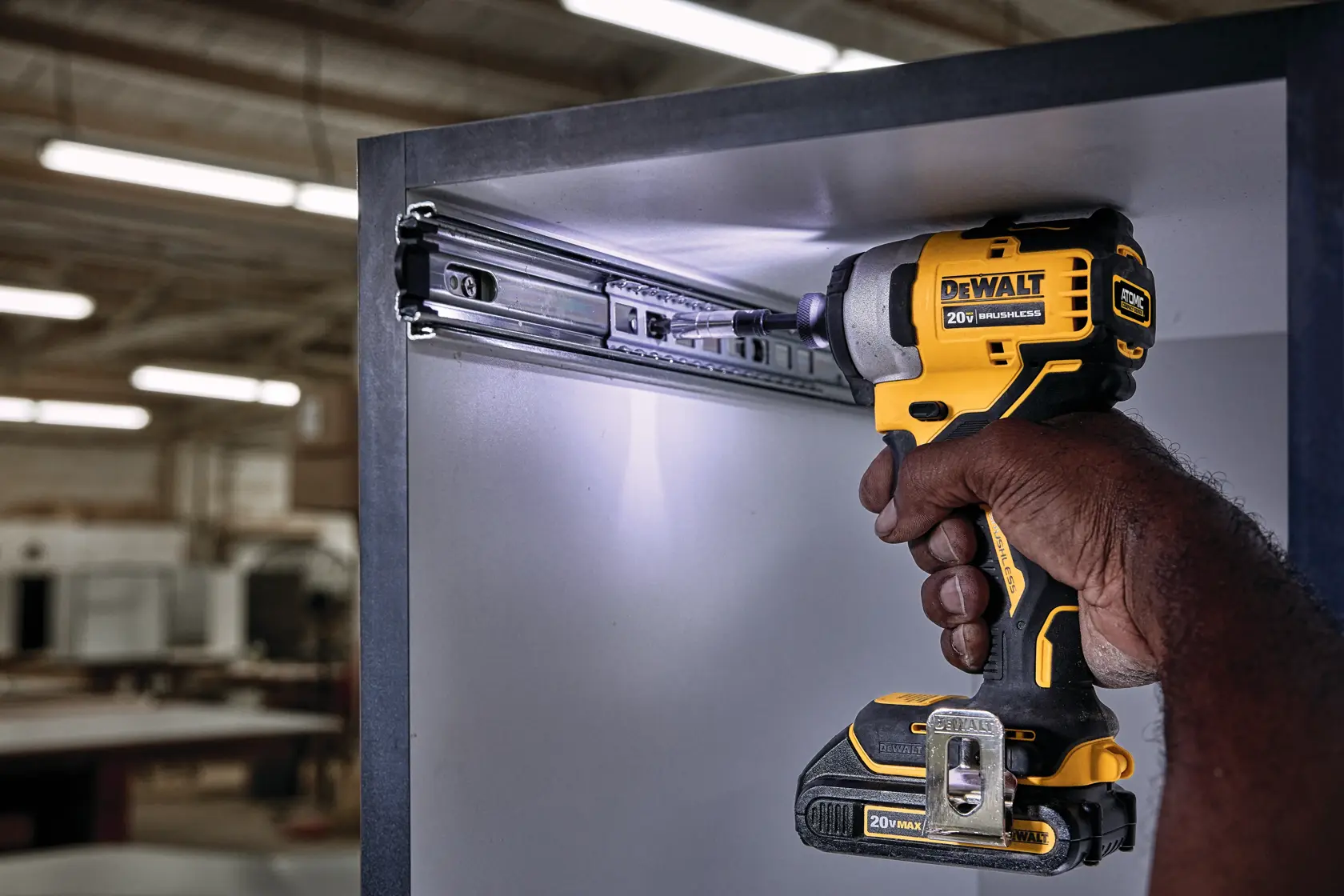 ATOMIC brushless cordless compact impact driver fastening screw through gliding rails on wood.