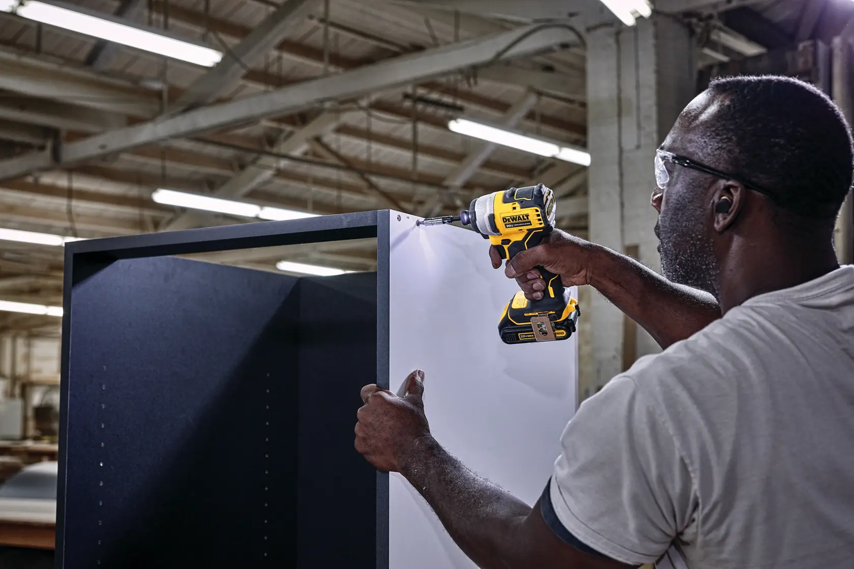 ATOMIC brushless cordless compact impact driver being used by person to fasten screw.