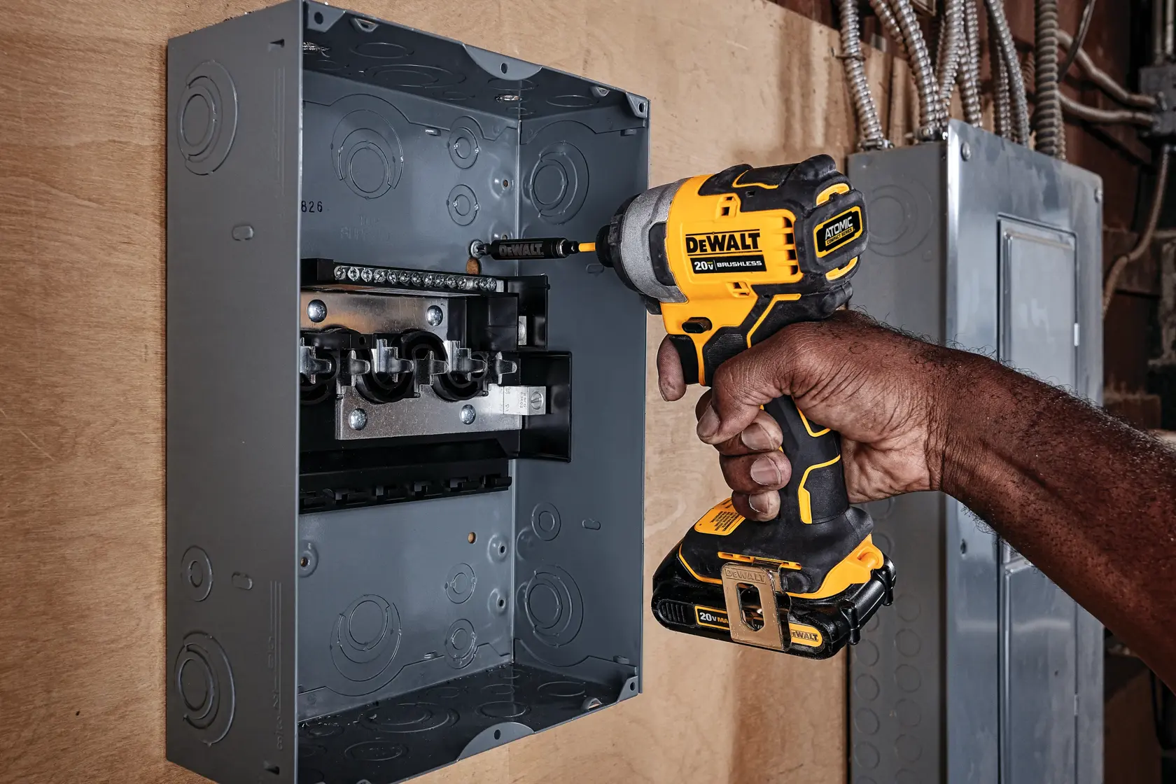 ATOMIC brushless cordless compact impact driver kit two battery kit fastening metallic box on wood.