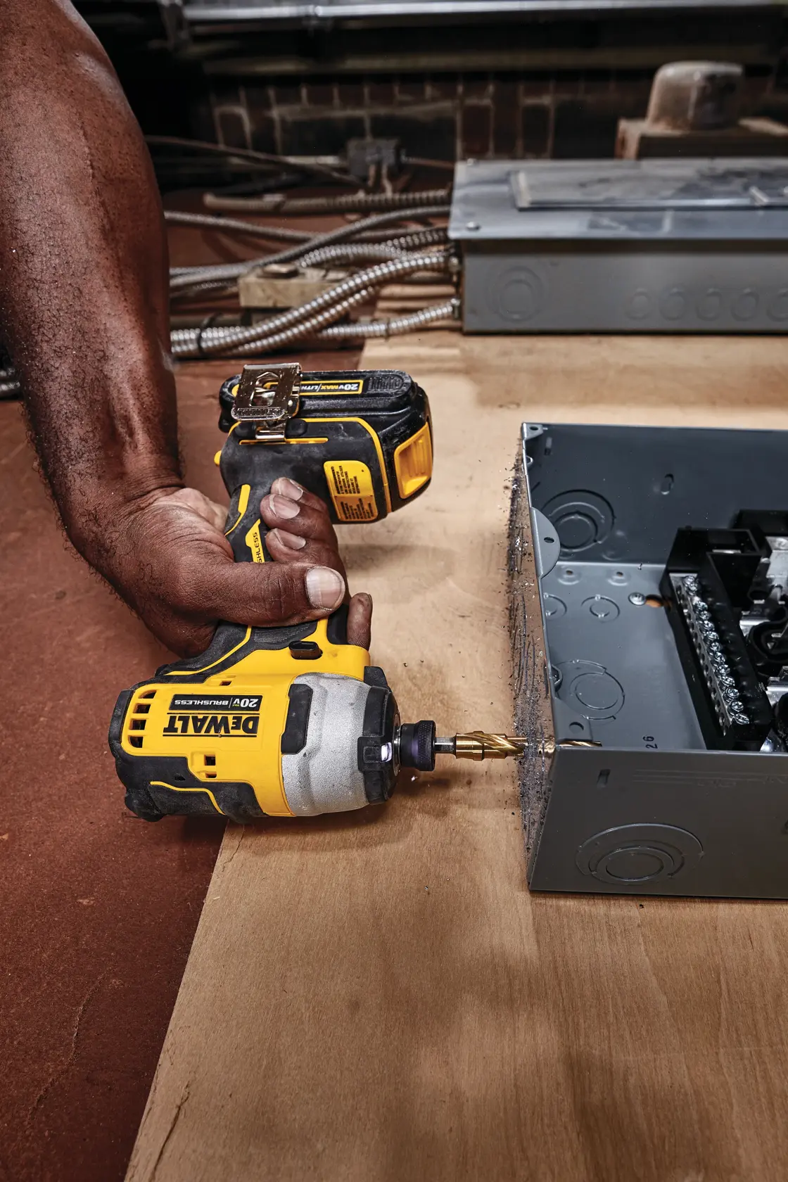 ATOMIC brushless cordless compact impact driver kit two battery kit drilling through a metallic box.