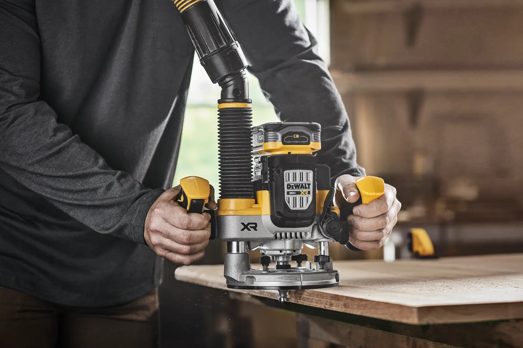 DEWALT XR 20V MAX* Plunge router with 20V MAX* XR 5 ah battery on wood surface in use dust shroud being used