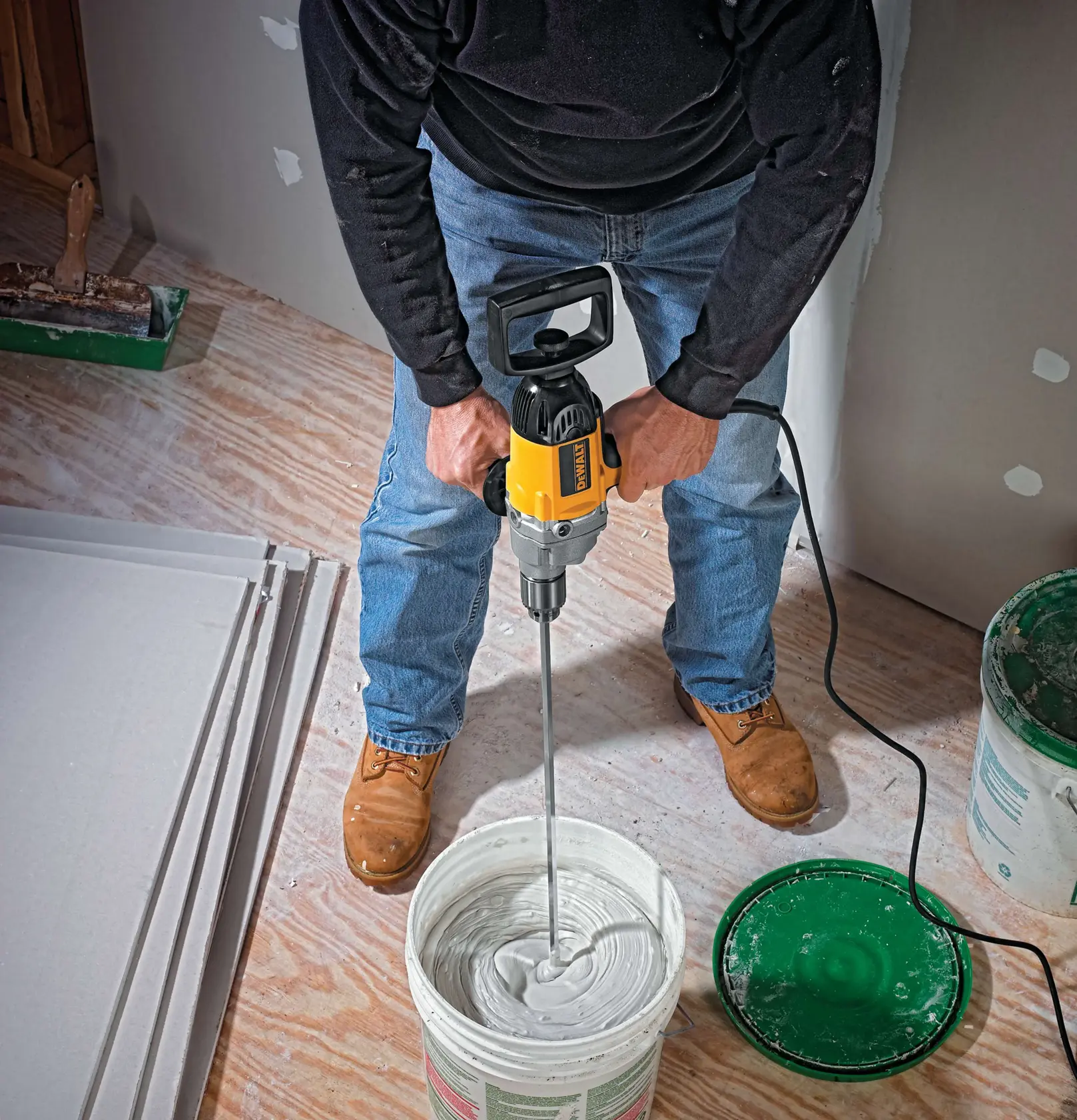 Half inch spade handle drill mixing concrete in a container.