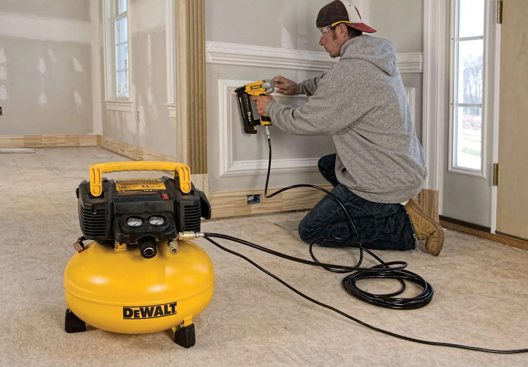 Heavy duty 165 pounds per square inch pancake compressor being used by a person to drill on wall.