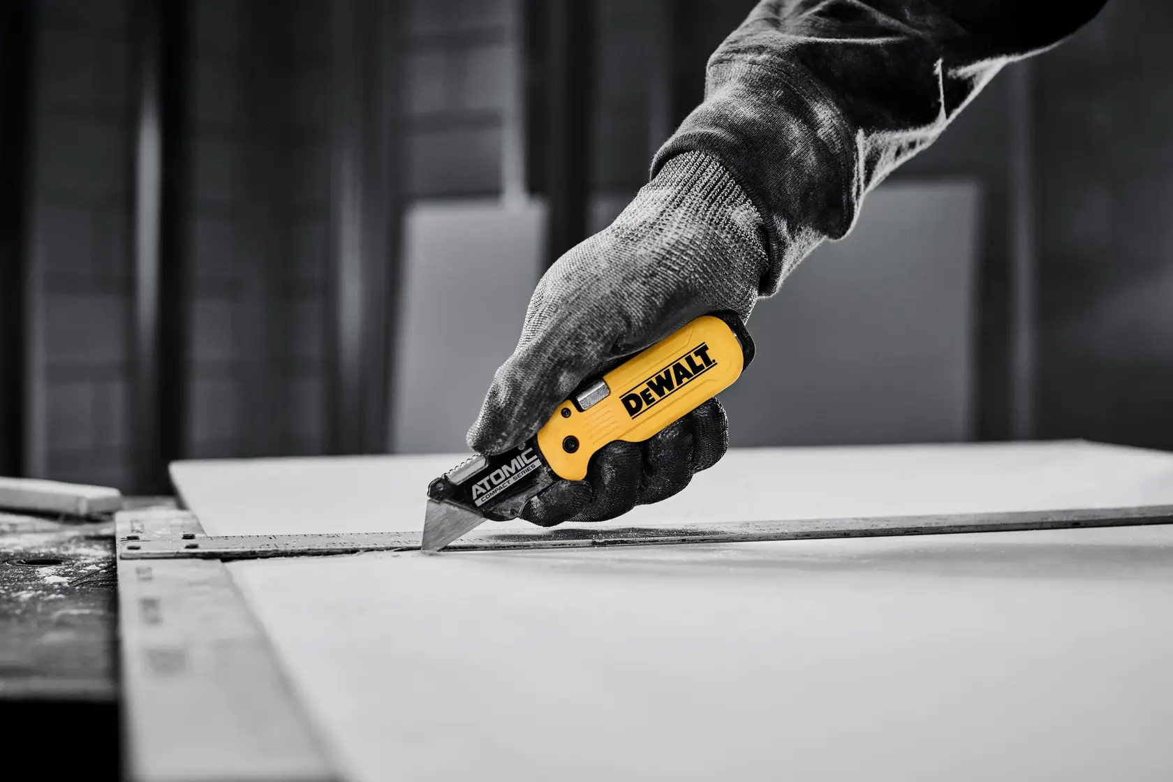 DEWALT ATOMIC knife cutting sheet of drywall with T-square as a guide