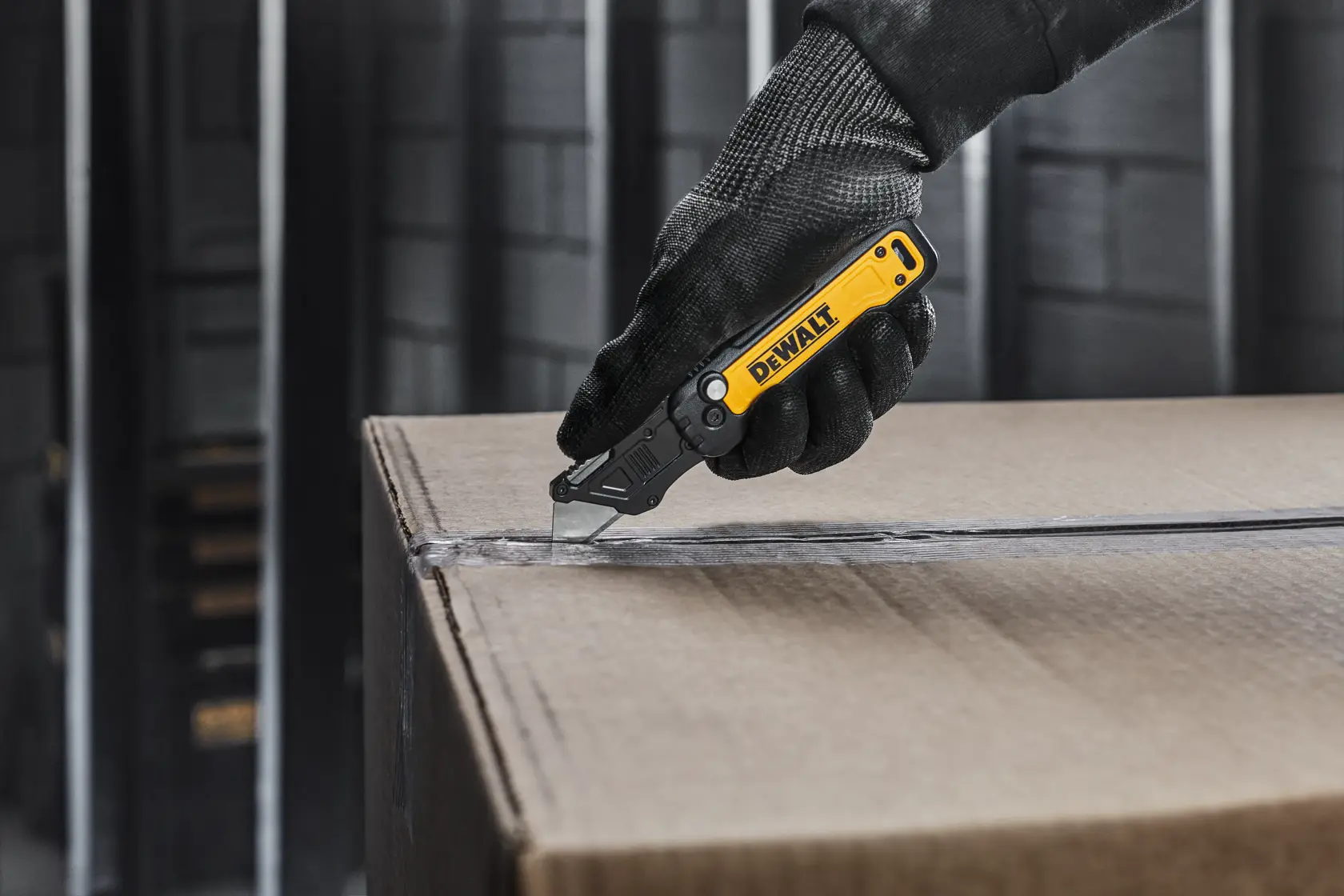 DEWALT knife with user cutting open a cardboard box