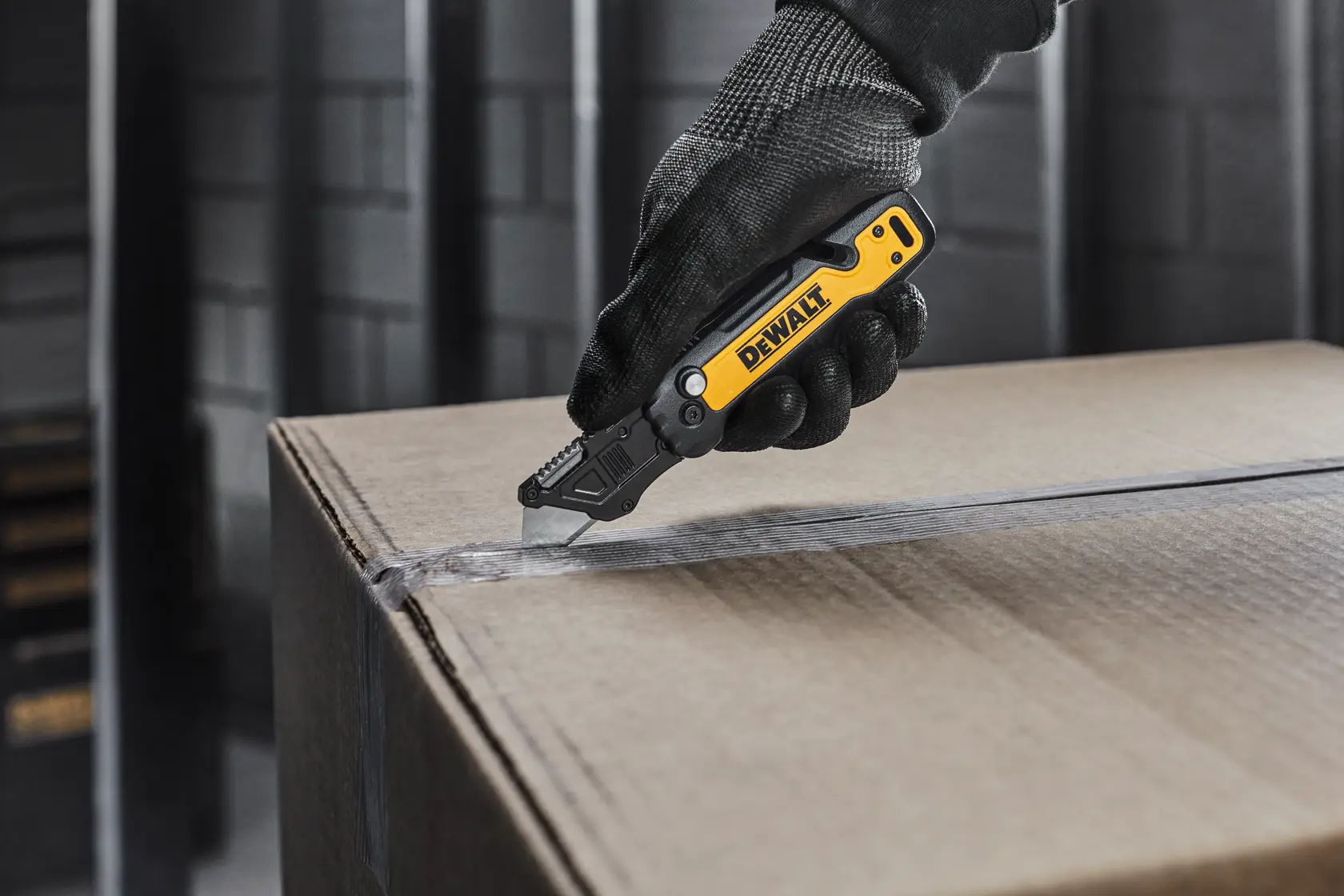 DEWALT knife with user cutting open a cardboard box
