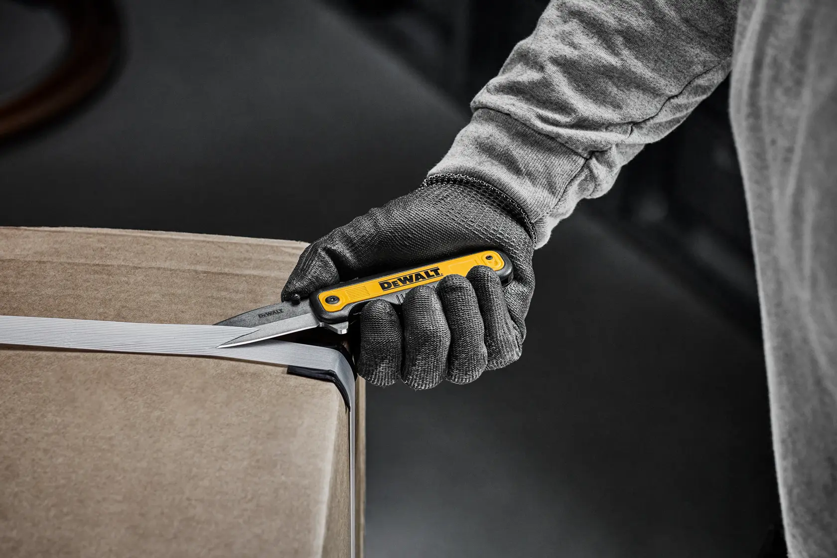 DEWALT pocket knife cutting straps on a cardboard box