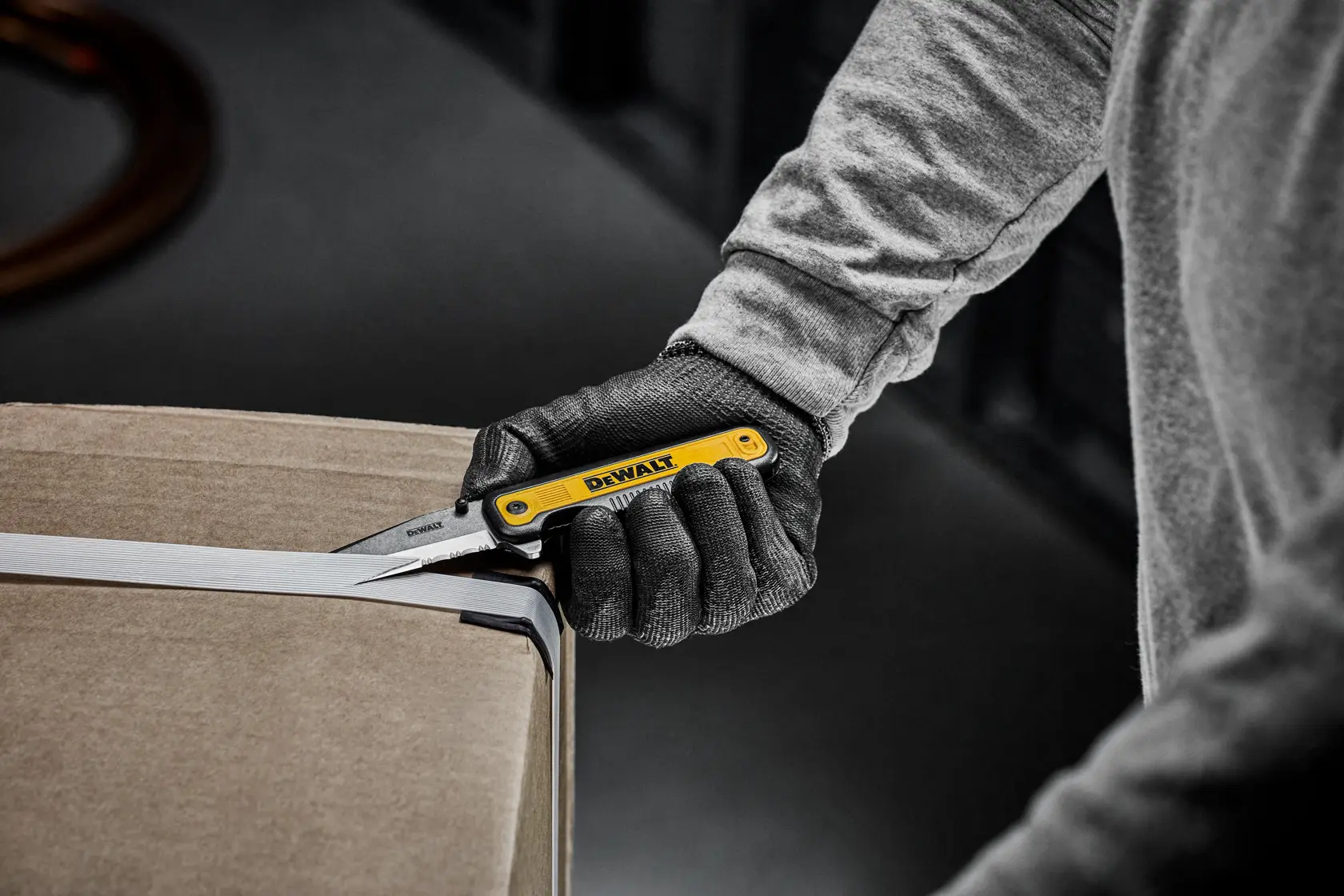 DEWALT pocket knife cutting straps on a cardboard box