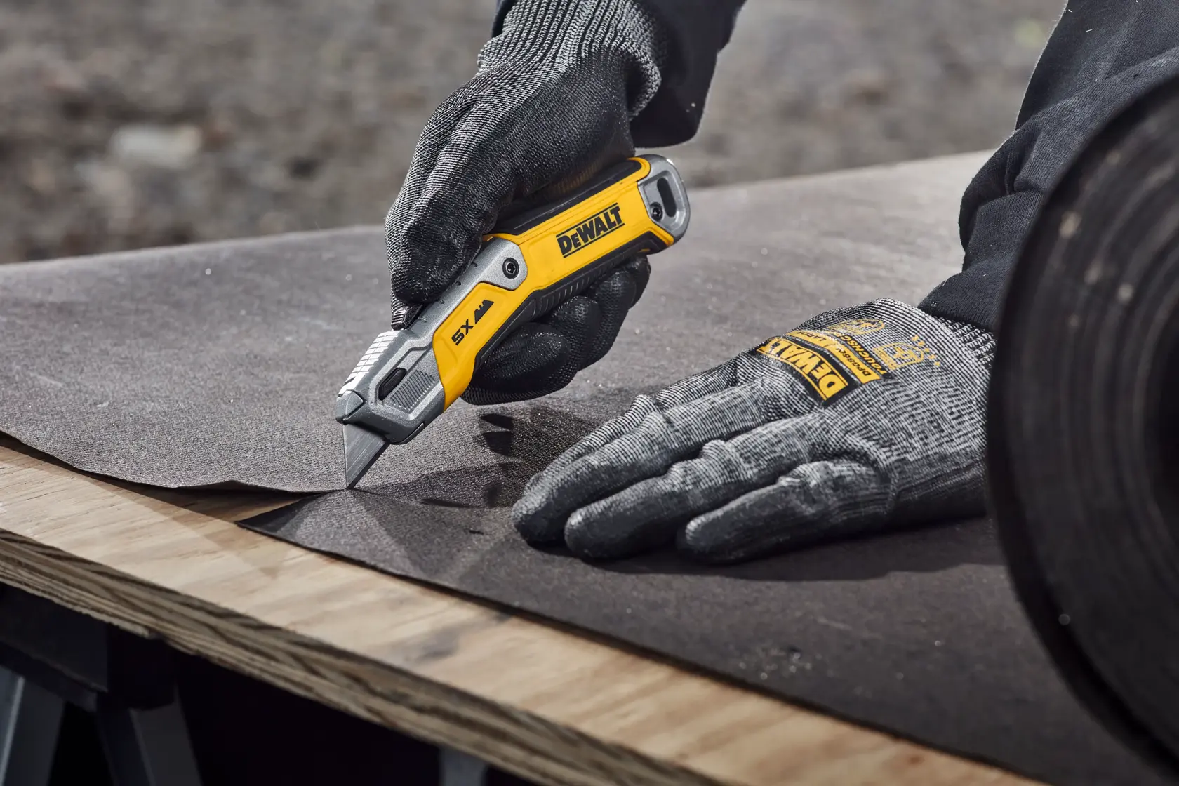Worker cutting tar paper on plywood surface with DEWALT® DWHT10998 Utility Knife