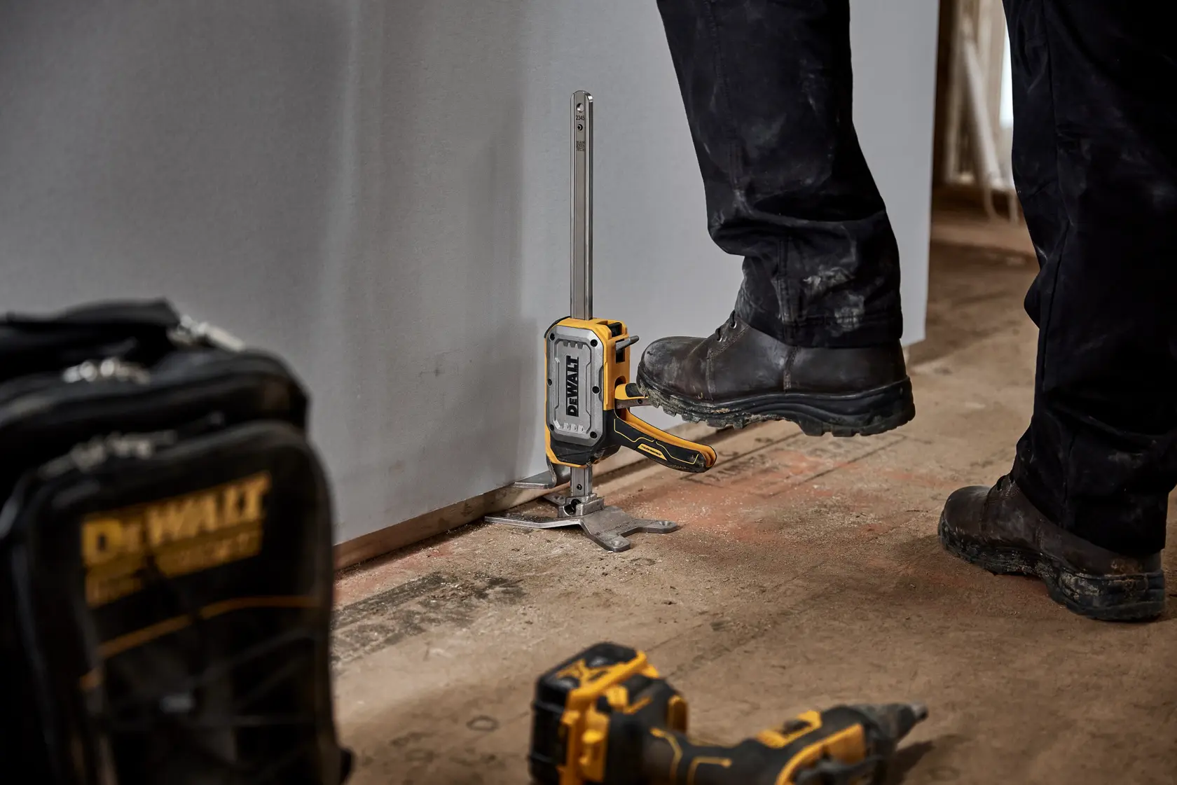 Worker lifting drywall with DEWALT(R) TOUGHSERIES(TM) CONSTRUCTION JACK step to lift feature
