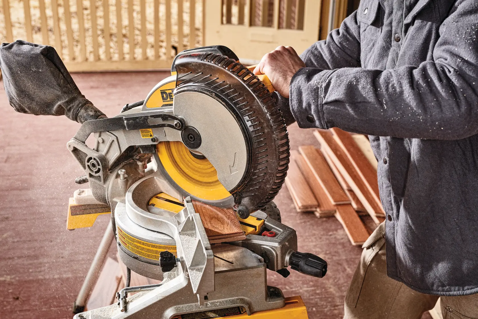 Electric single bevel compound miter saw being used to cut wood.