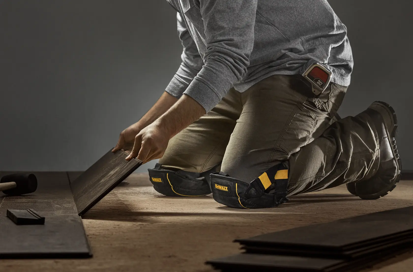CONSTRUCTION PRO WEARING DEWALT FLOORING KNEE PADS WITH GEL WHILE